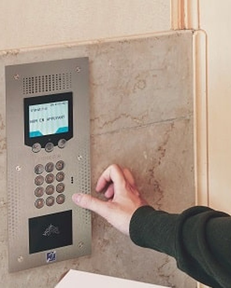 Résident utilisant une platine d'interphone Intratone dans un hall d'immeuble